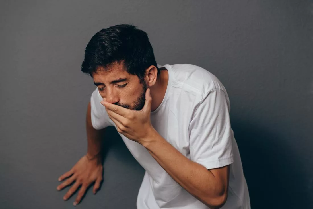 man about to vomit green or yellow bile covering his mouth with his hand jpg